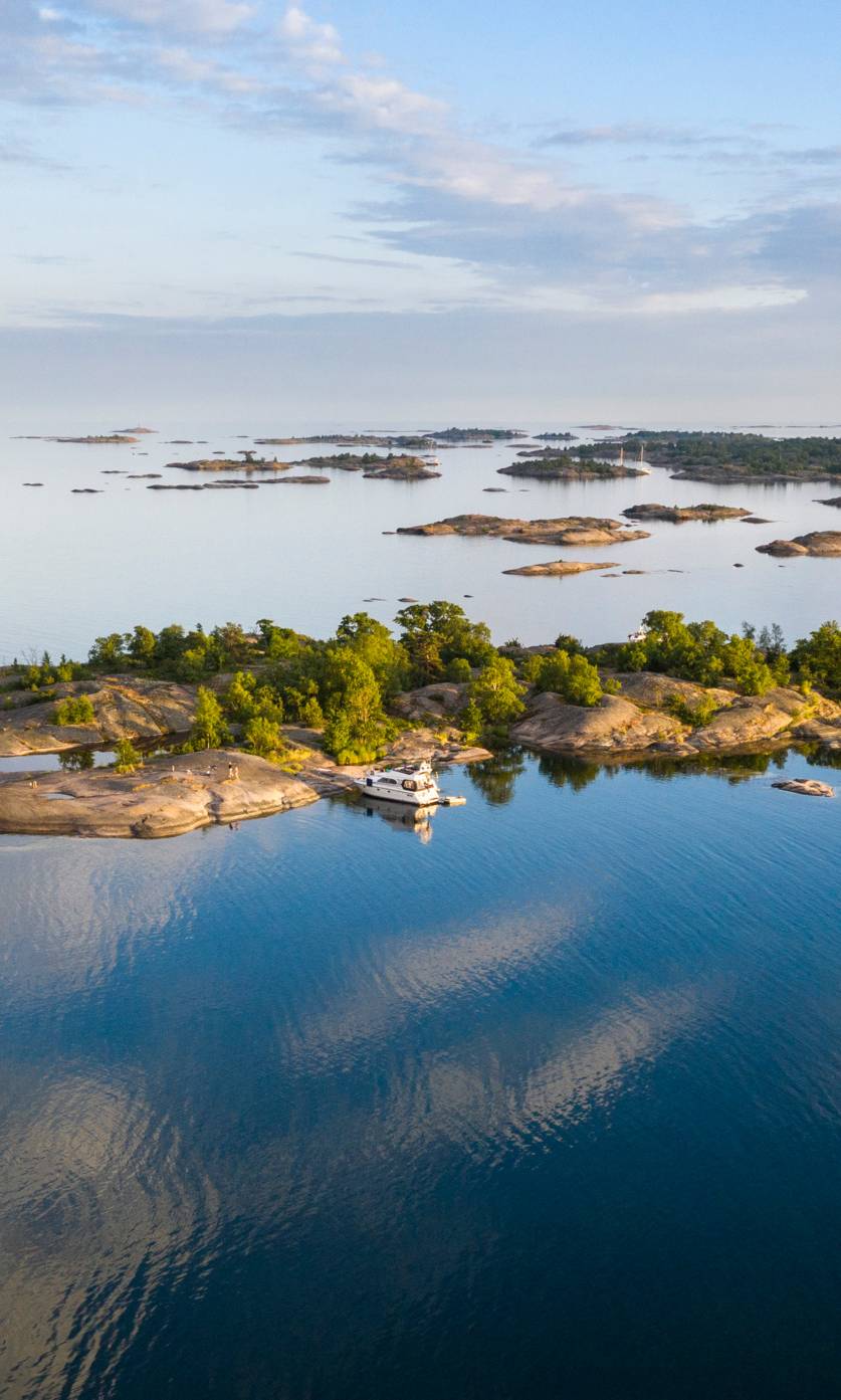 Aerial image of a boat next to an island in the Stockholm archipelago during a summer day.