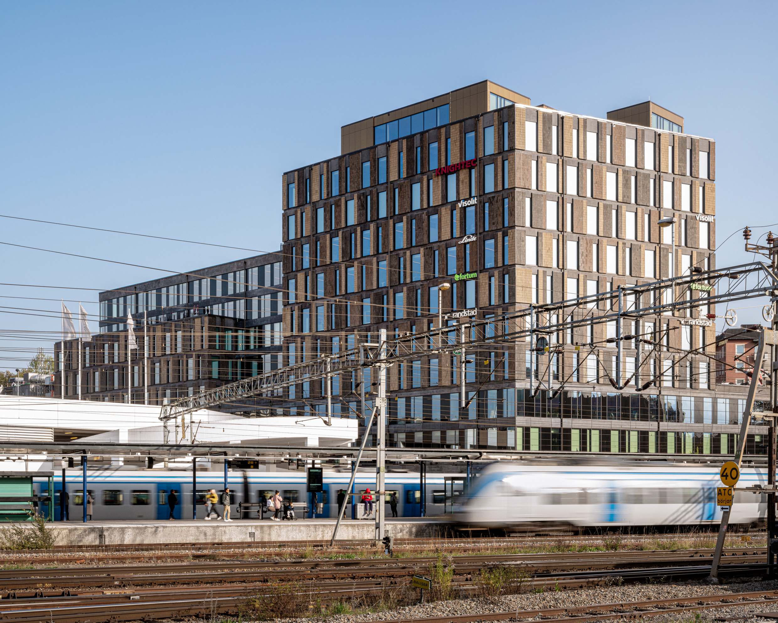 A rail train passes by an office area.