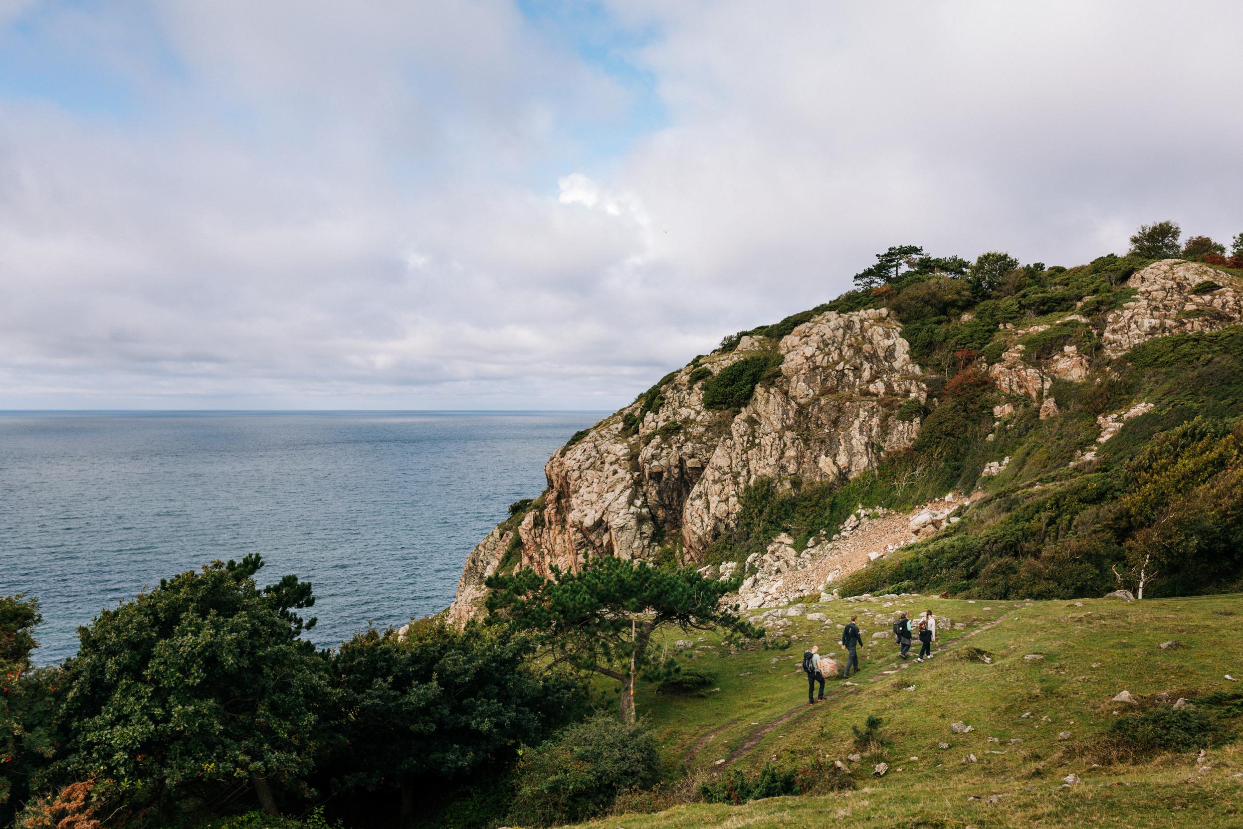Personen wandern an der Küste der Halbinsel Kullaberg auf dem Kullaleden.