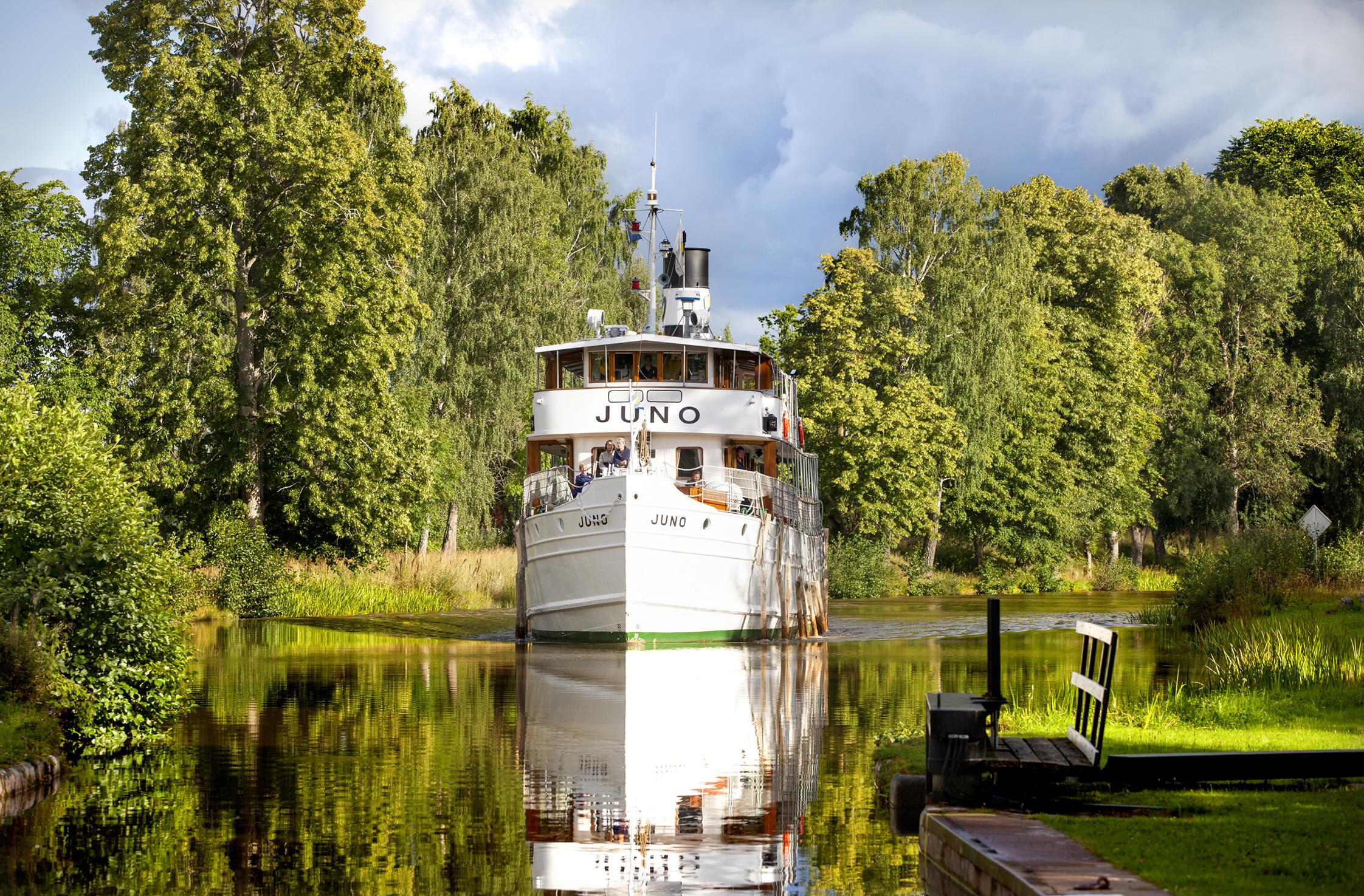 Een boot vaart door het Götakanaal. Op de oevers staan bomen.