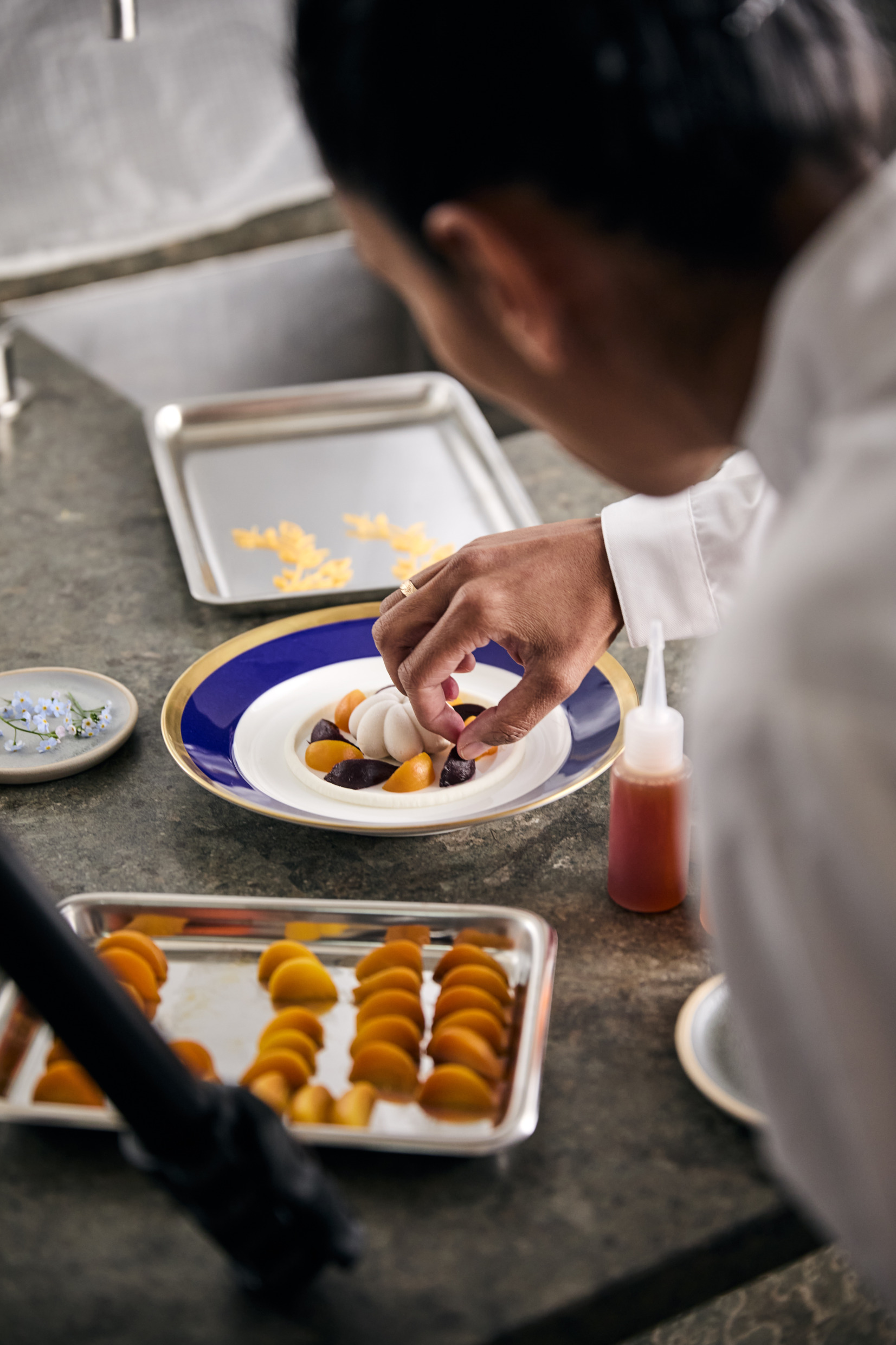 A chef plating a dessert in a professional kitchen.