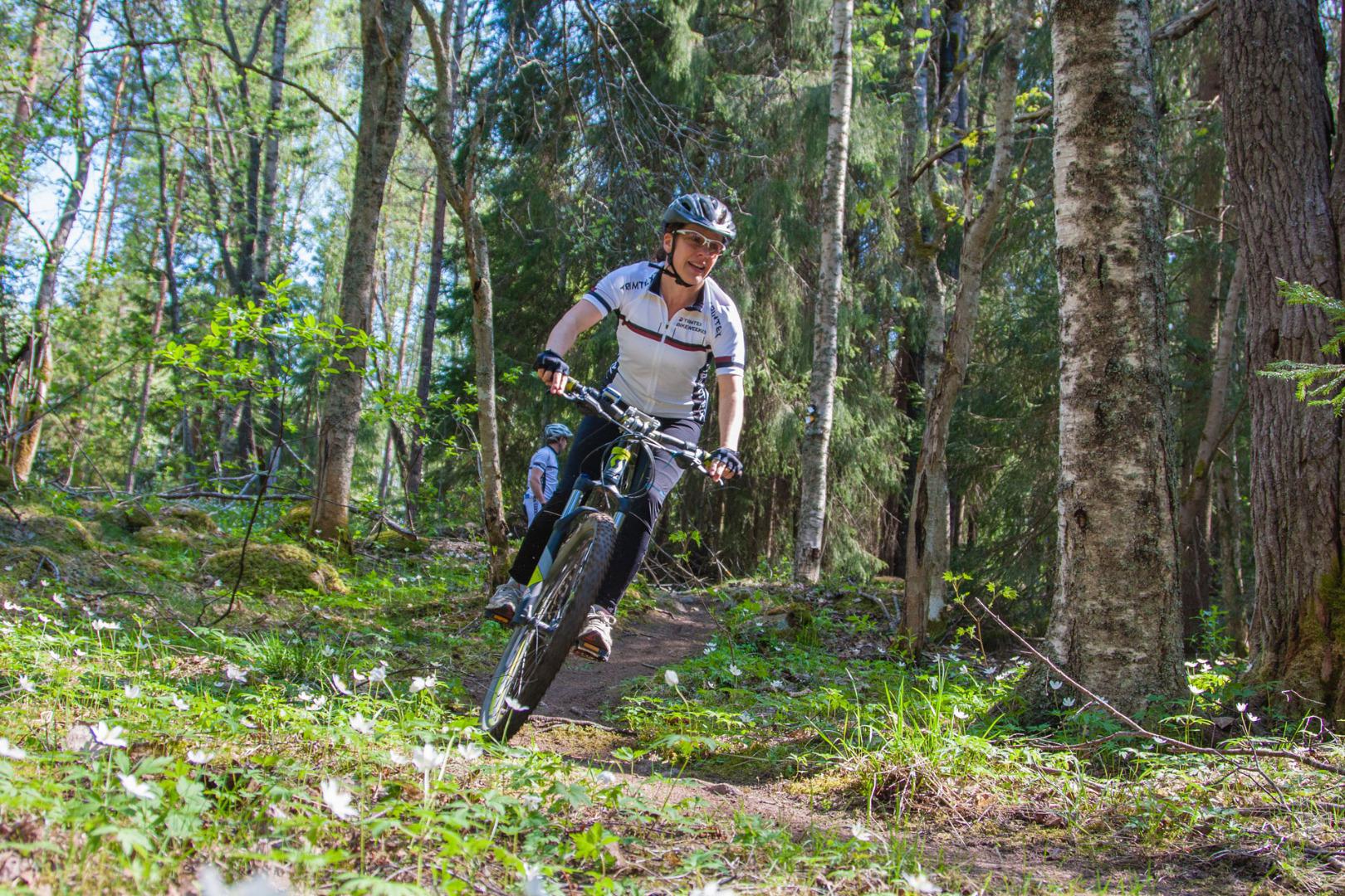 Een vrouw is aan het mountainbiken op een parcours in een bos in de zomer.