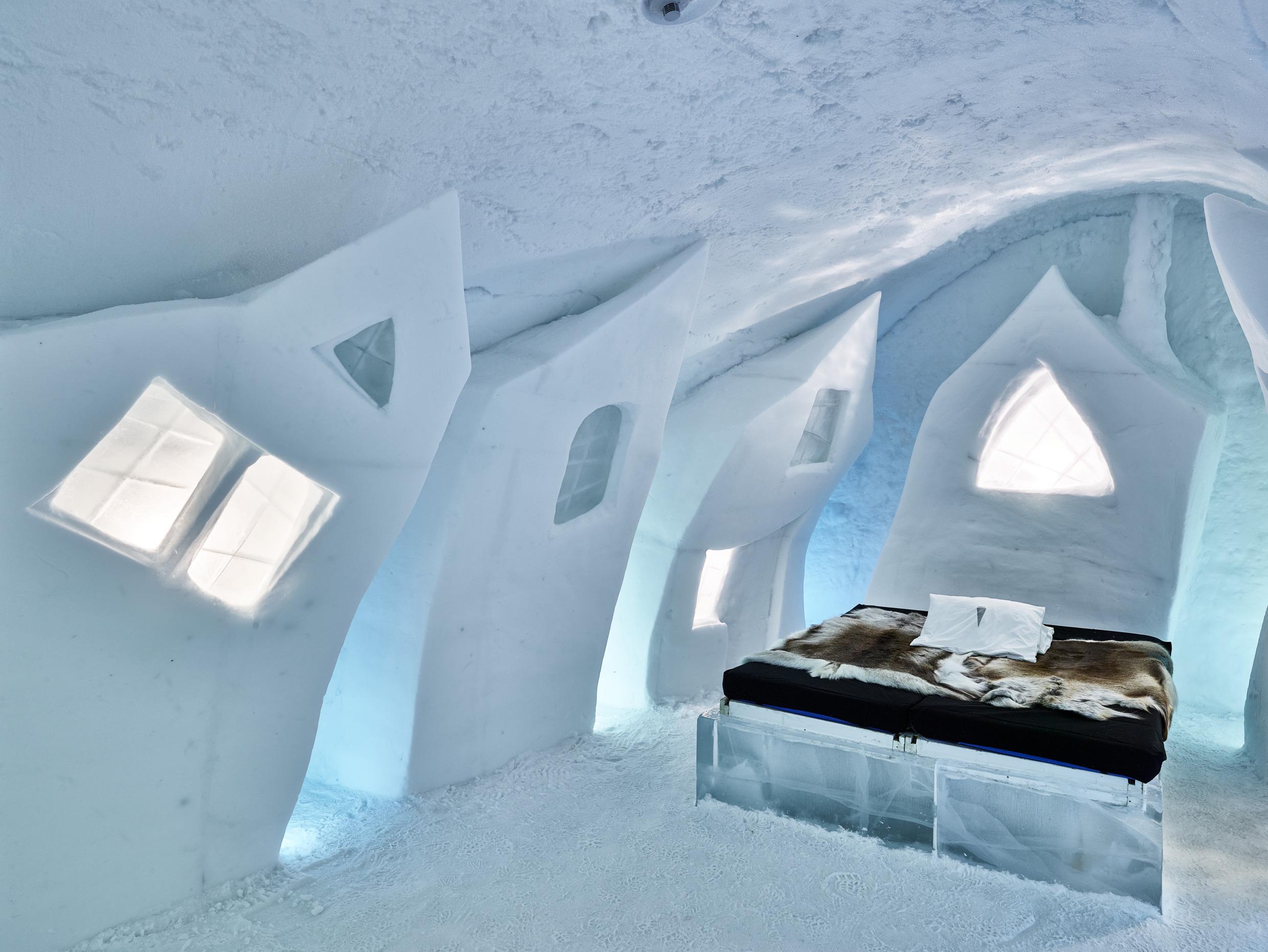 De binnenkant van een kamer in het Icehotel, geheel gebouwd van ijs. De kamer is artistiek, met asymmetrische ijsramen en een dierenhuid op het bed.