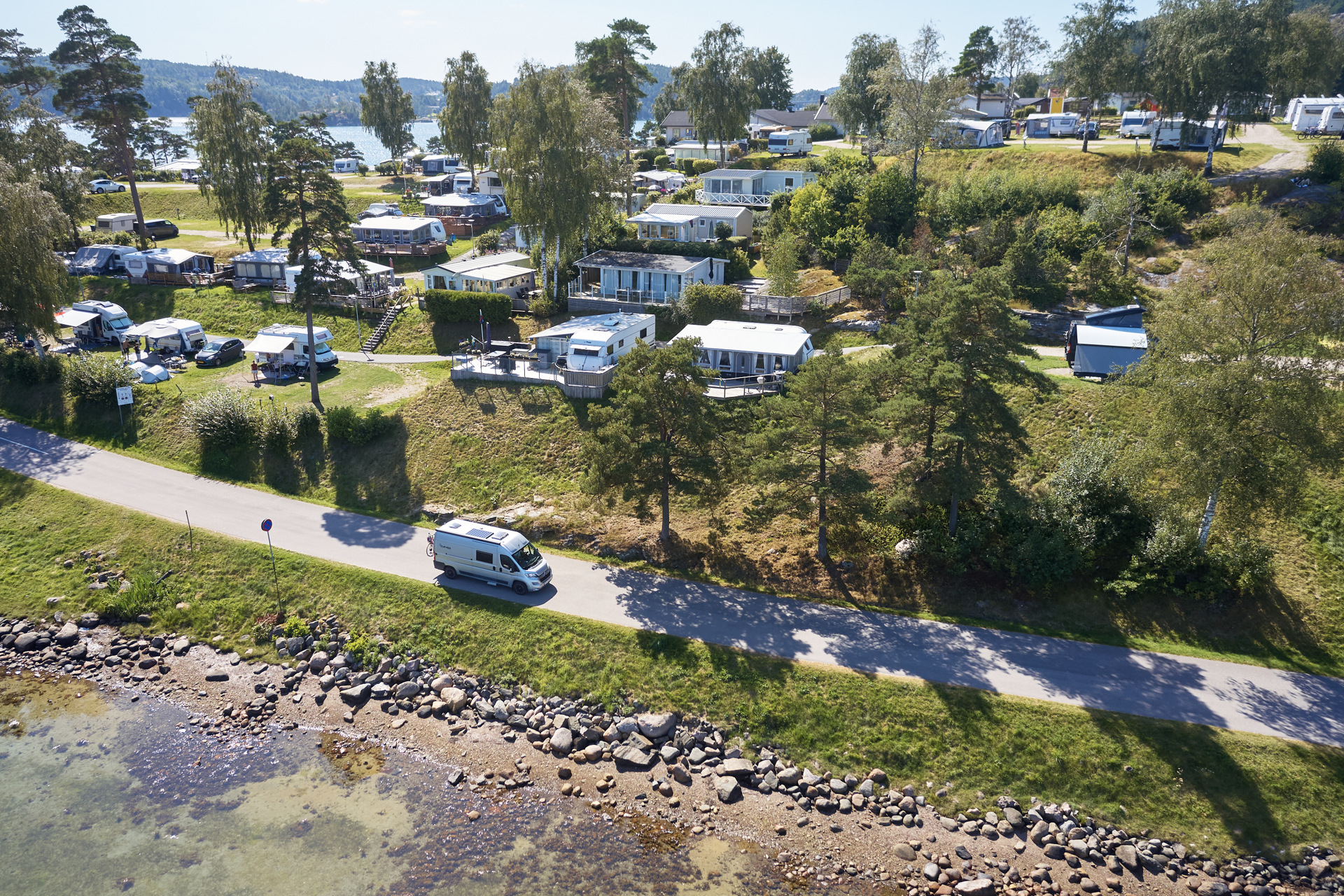 Coastal campsite in Bohuslän with caravans, cabins and sea views along a rocky shoreline.