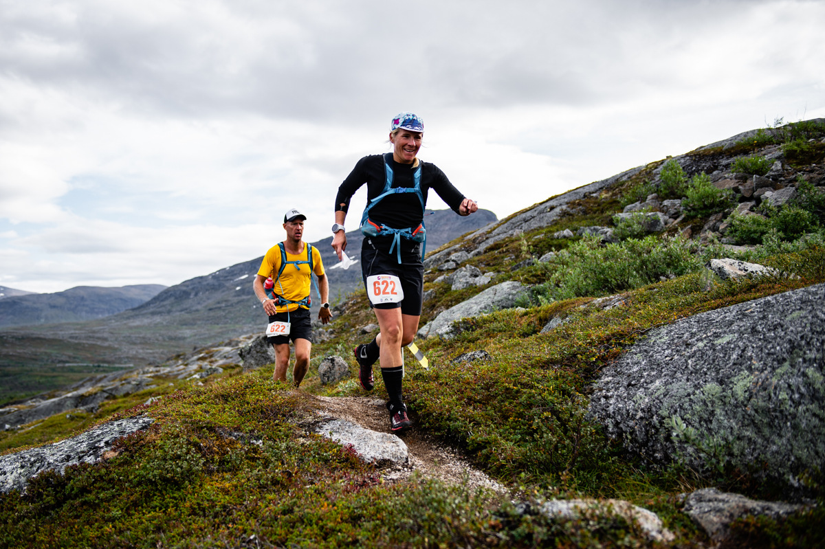 Deux coureurs de trail participant à la BAMM, courant sur un sentier de montagne rocailleux près de Kiruna, dans un paysage arctique.