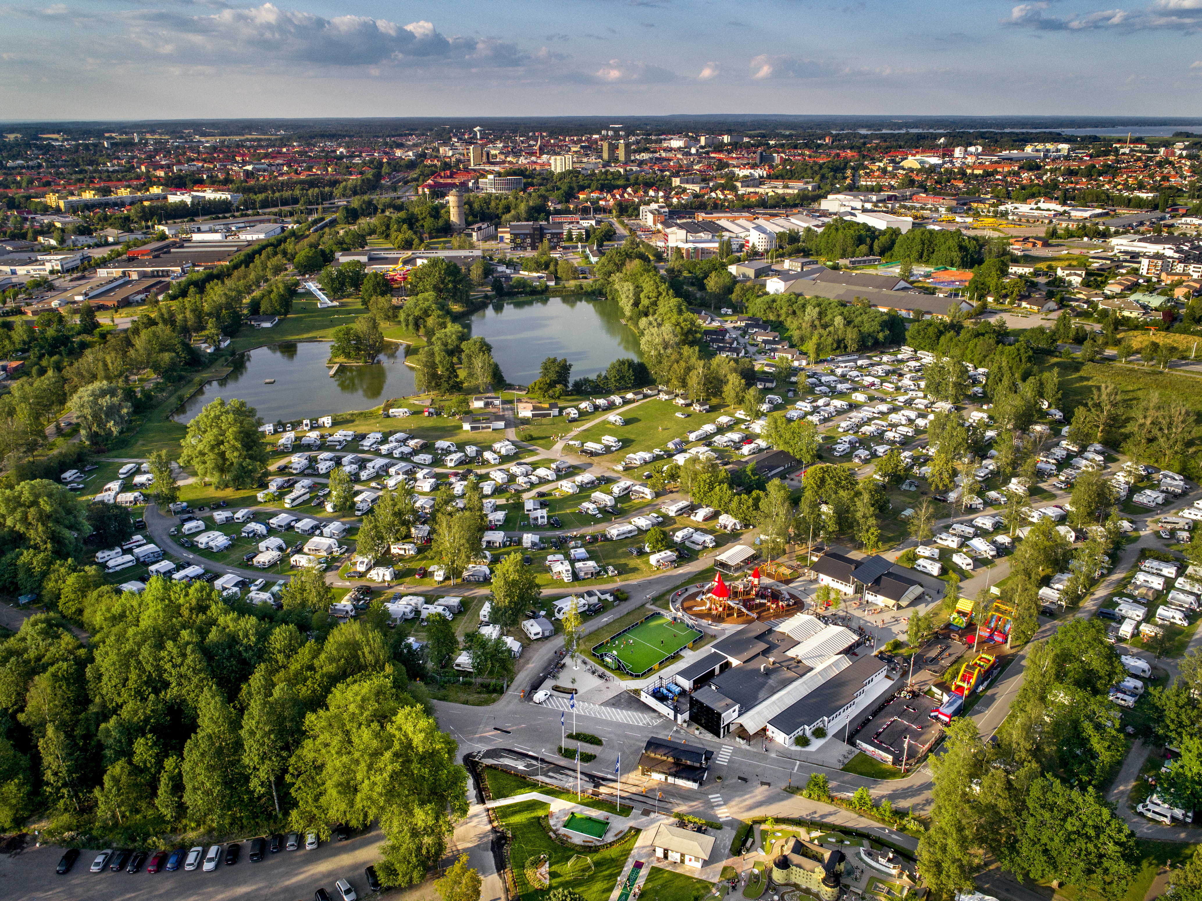 Aerial view of Gustavsvik Camping in Örebro with caravans, green areas and a lake near the city.