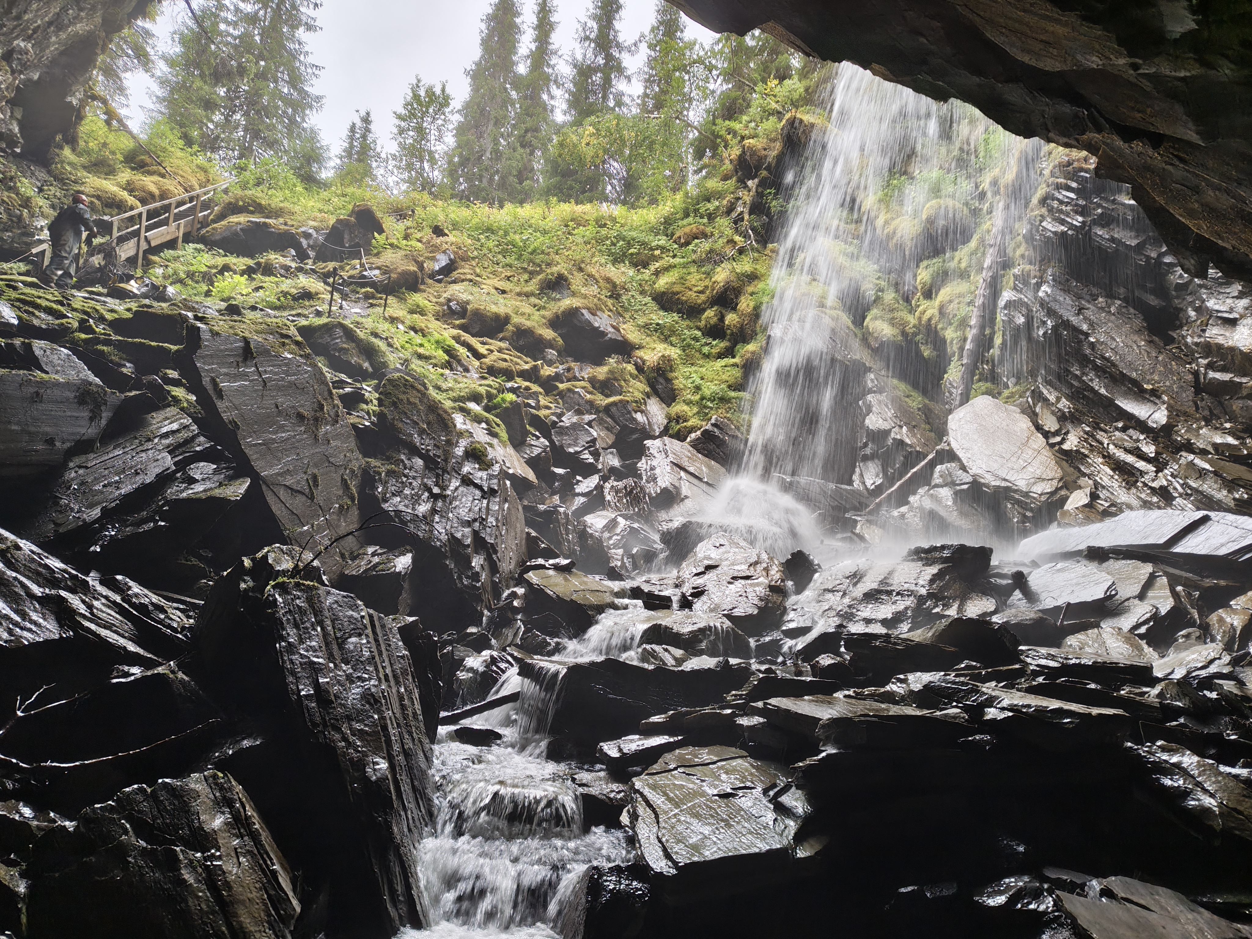 Een uitzicht vanuit een grot op een open plek en een waterval.