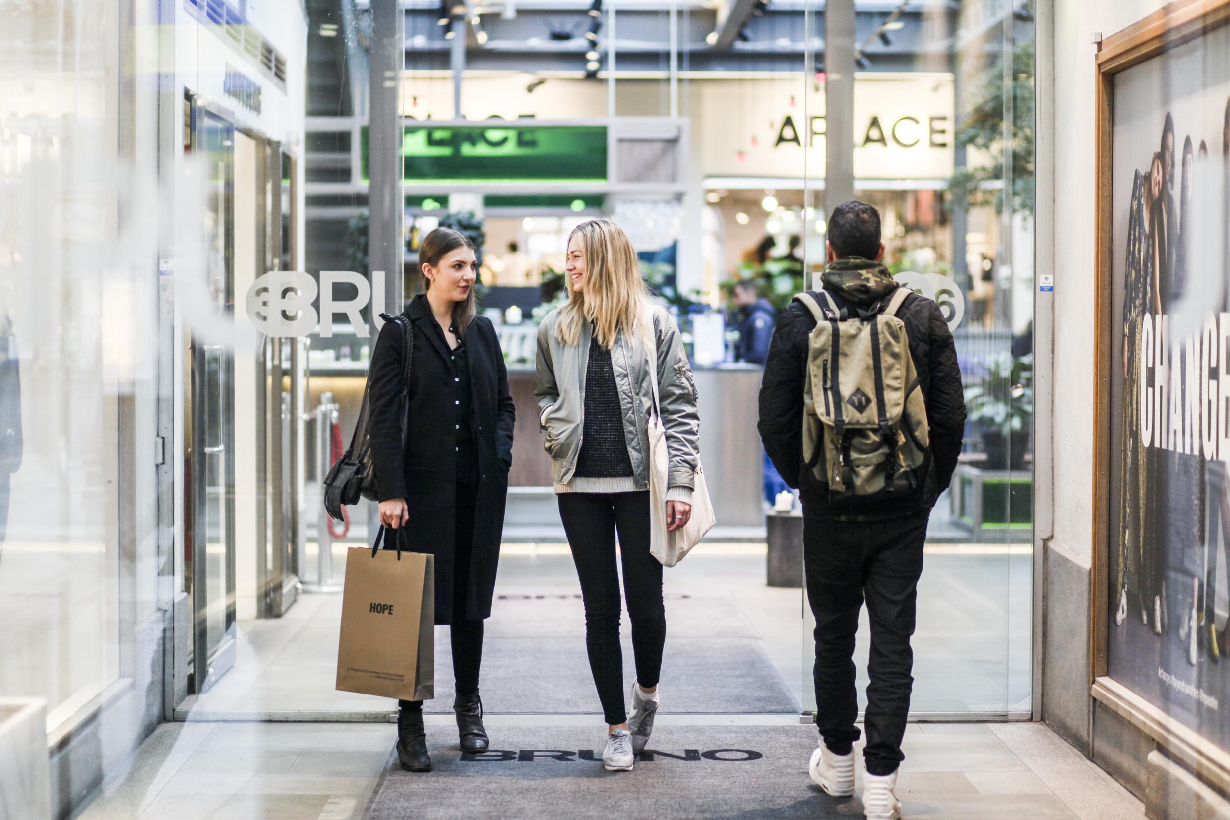 Een man met een rugzak verlaat een winkel in Stockholm terwijl twee vrouwen binnenkomen.