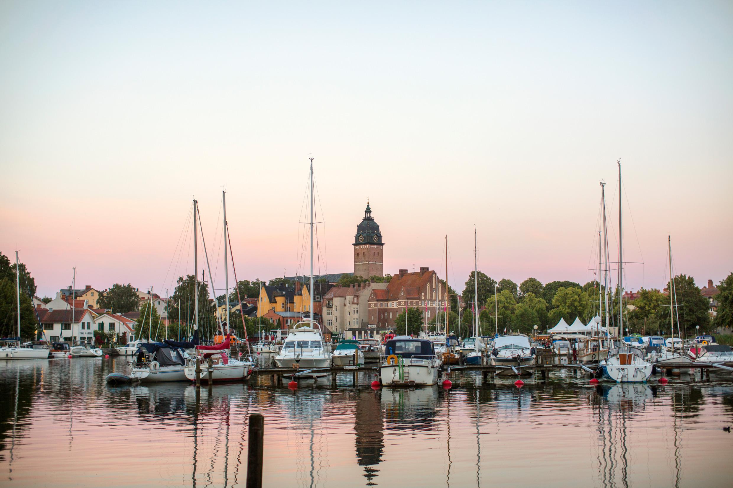 A town by the lake with a dock filled with smaller boats.