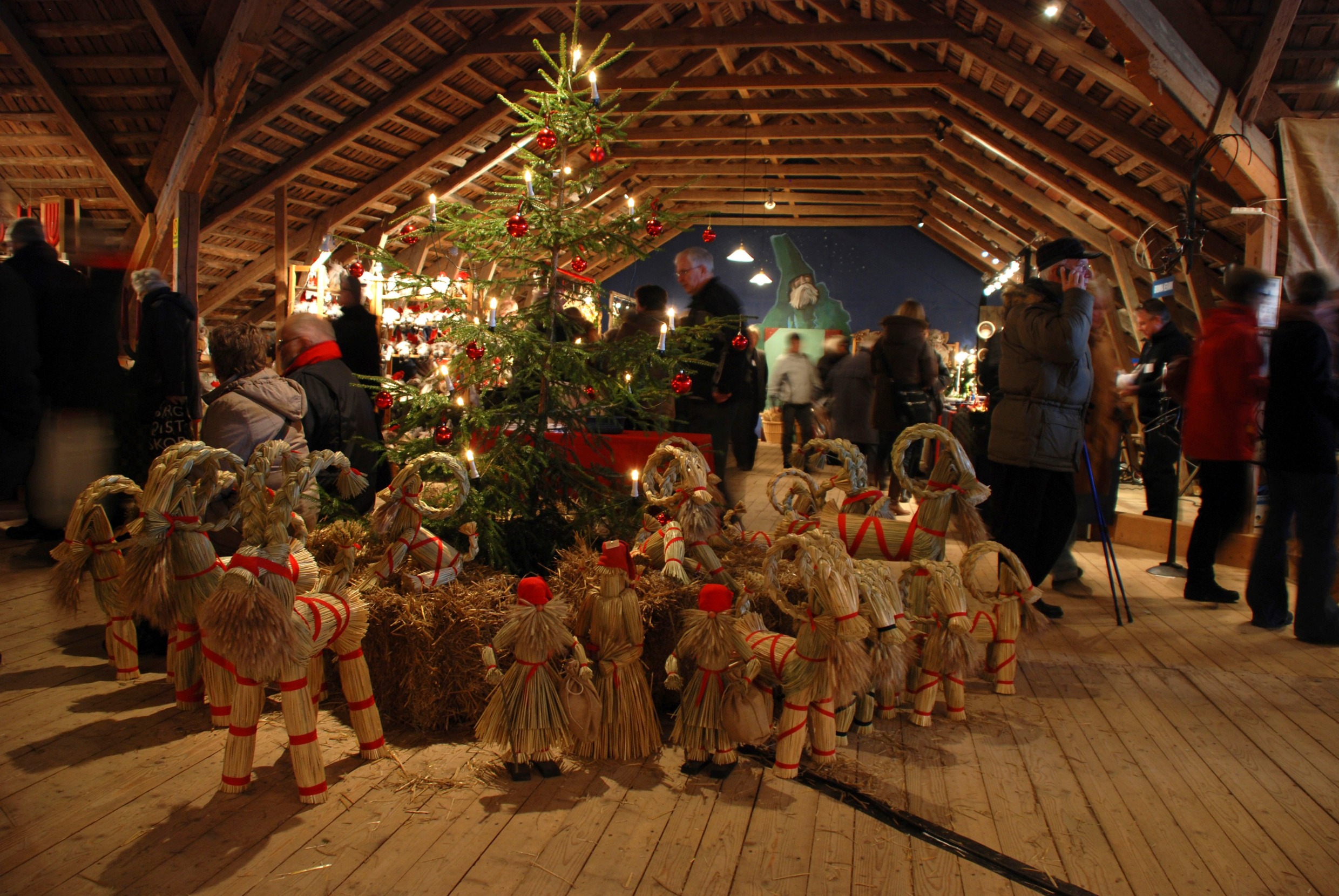 Indoor Christmas market at Mårbacka, with straw goats, red ornaments and visitors browsing stalls.
