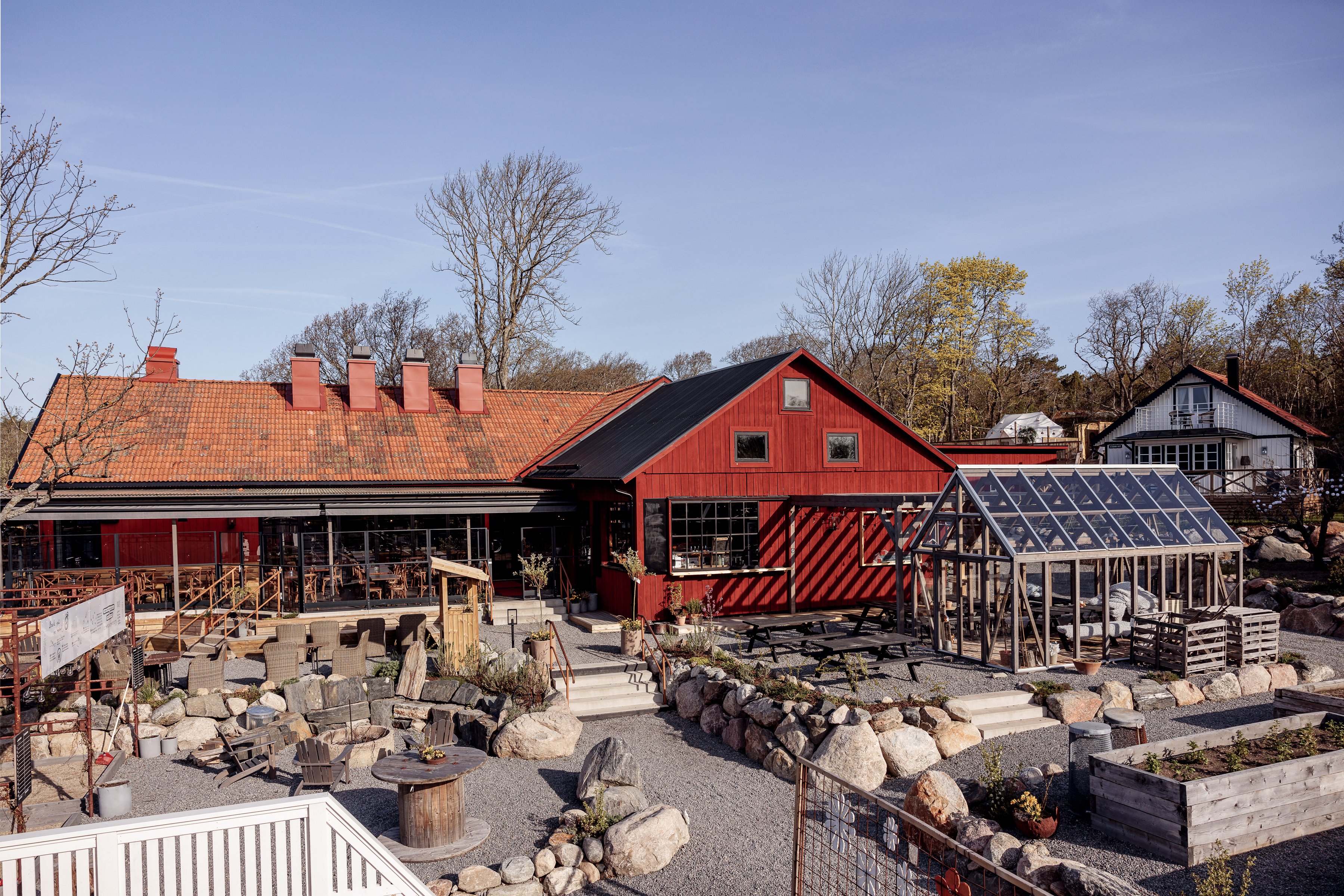 A red building with a greenhouse on the right hand side.