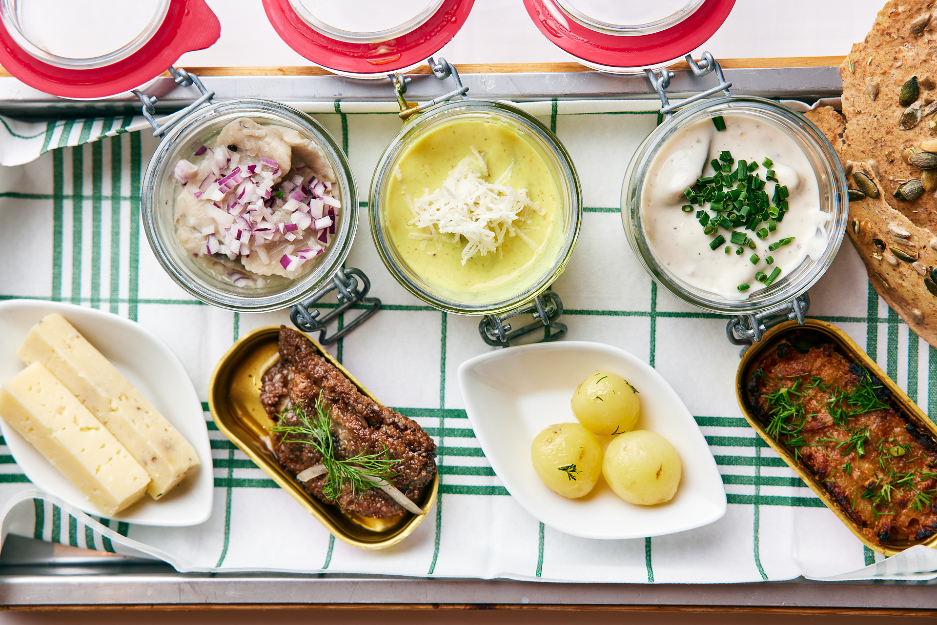 Kleine Schüsseln mit Kartoffeln, Hering, Fleisch und Käse, von oben fotografiert.