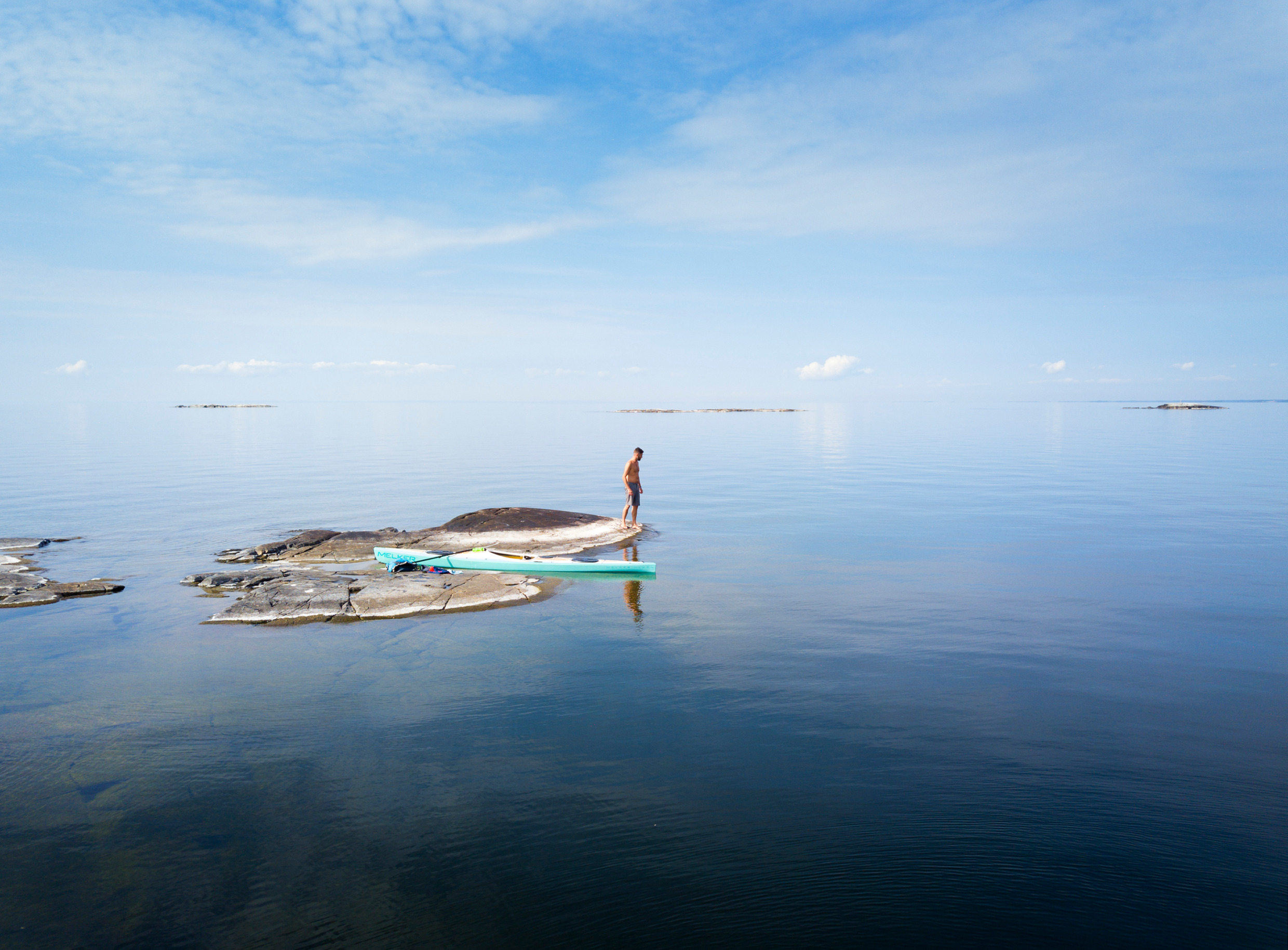 A person is standing on a small island in Lake Vänern. There is a kayak on the island.