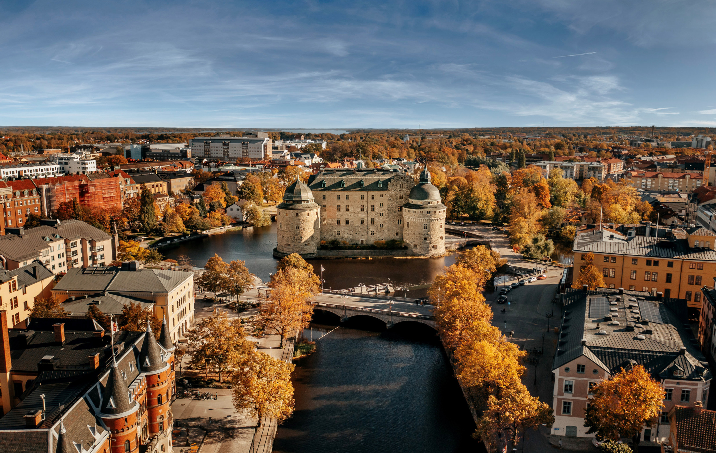 Der Blick von oben auf die Burg von Örebro zeigt sie umgeben von herbstlich gefärbten Bäumen und den Gebäuden der Stadt.