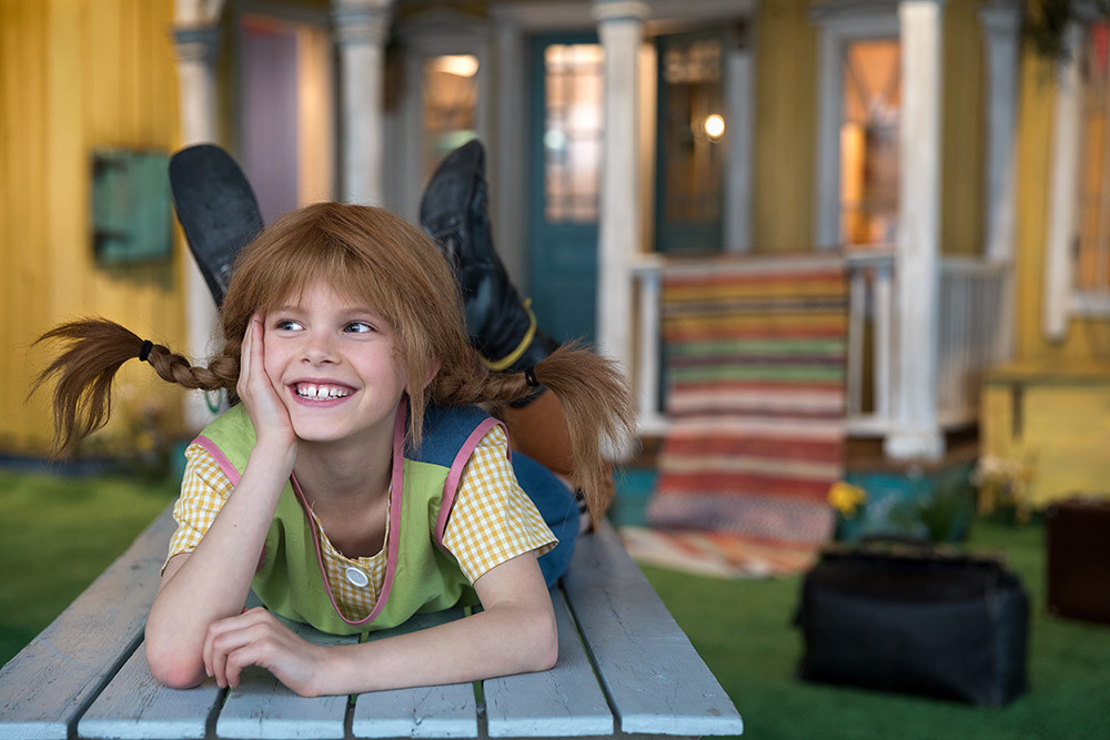 Pippi Longstocking lying on her stomach in front of Villa Villekulla.