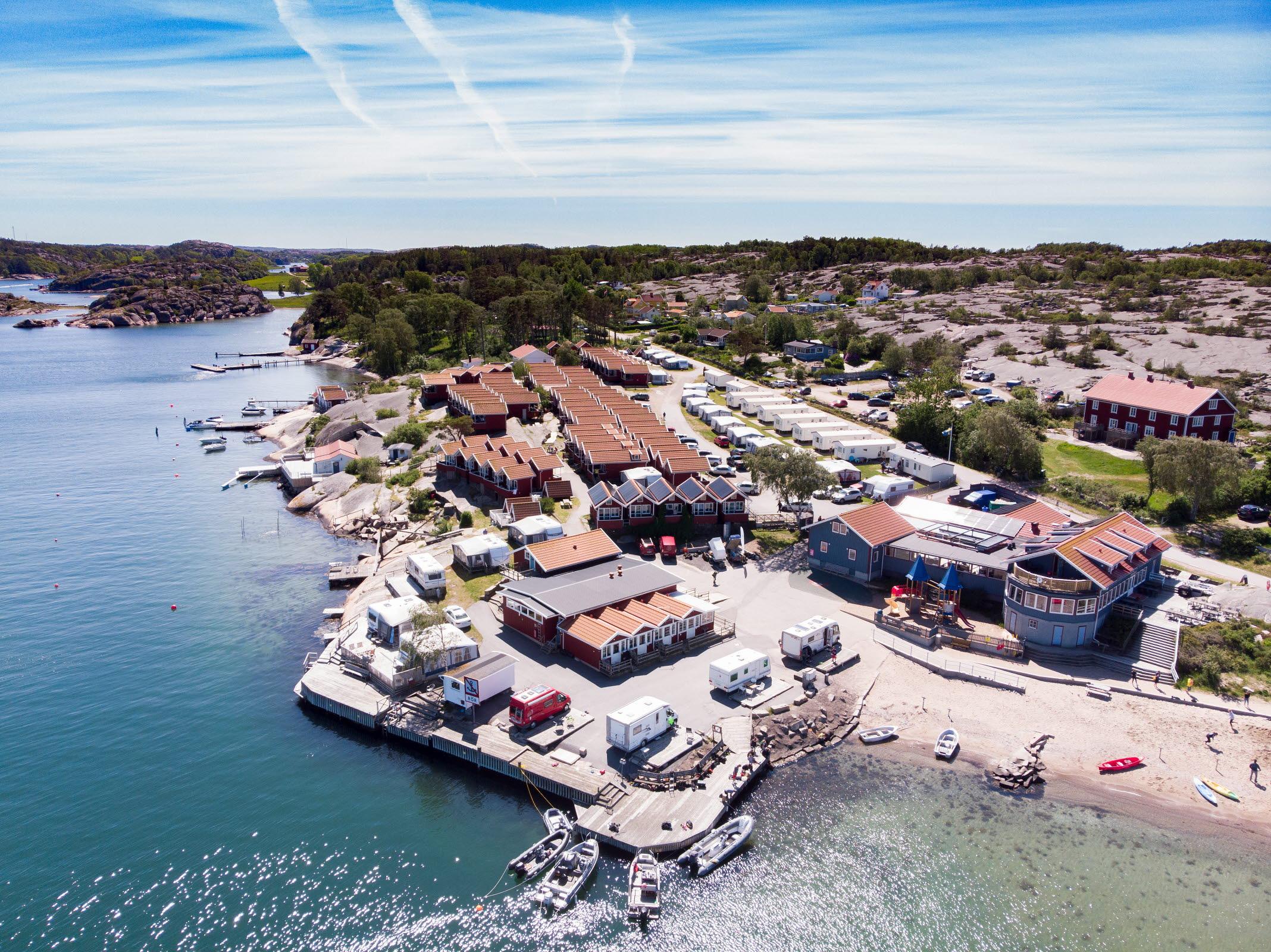 Luchtfoto op Ramsvik met huizen dicht bij de zee en rotswanden op de achtergrond. Een zonnige dag.