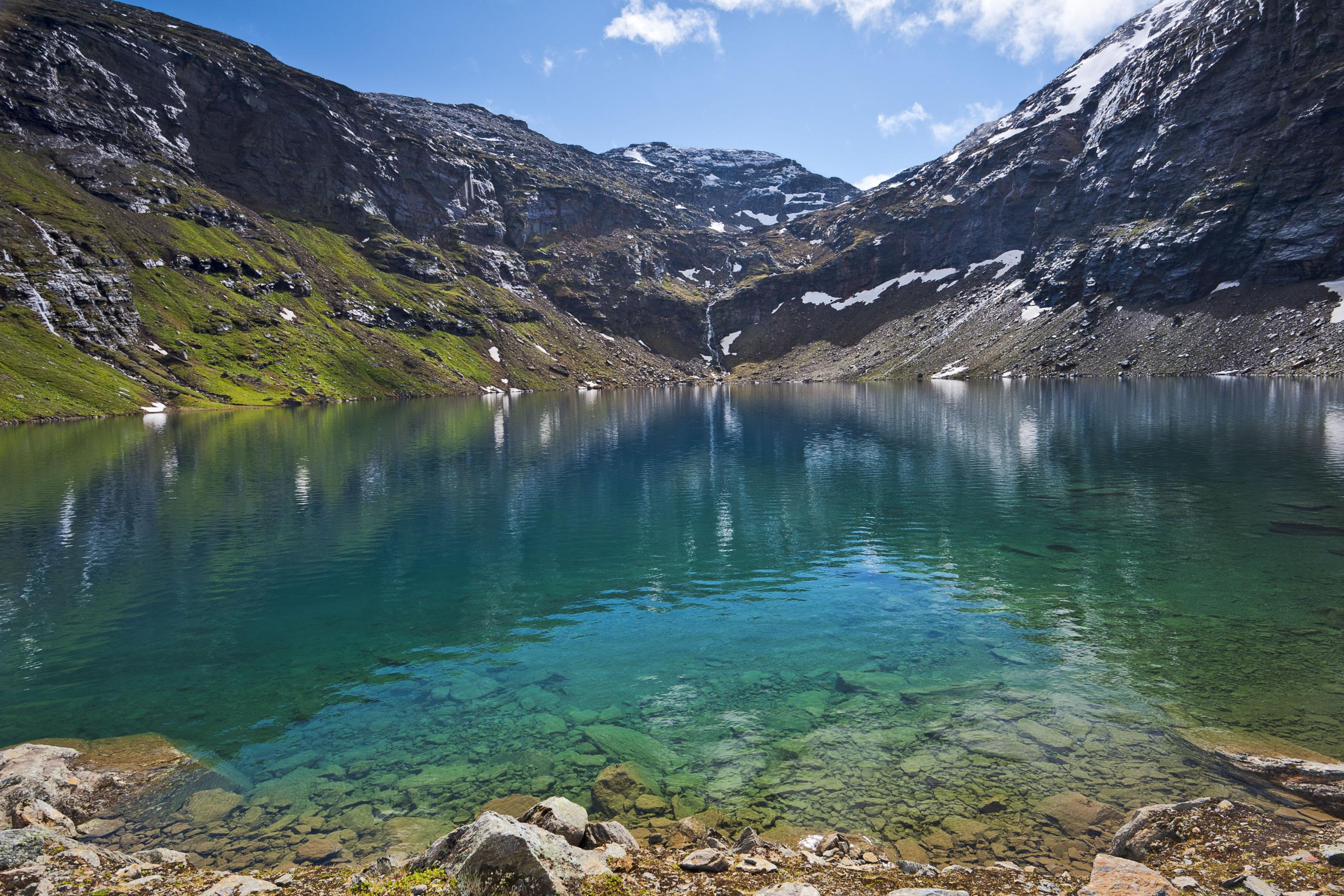 Ein blauer See, umgeben von Bergen, an einem Sommertag.