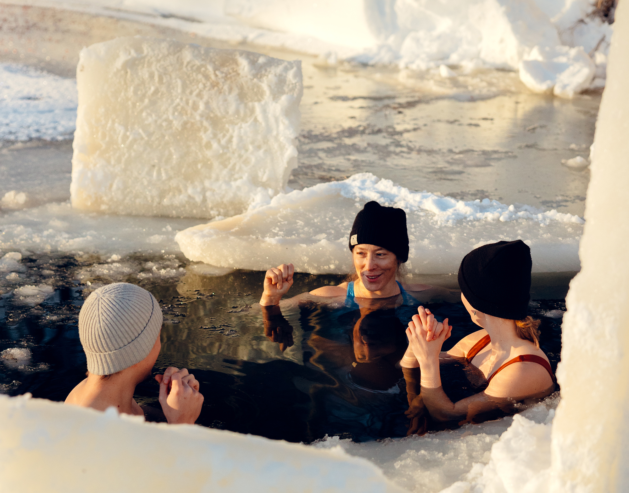 Trois personnes profitent d'une baignade hivernale au milieu des blocs de glace au centre de bains froids d'Umeå.