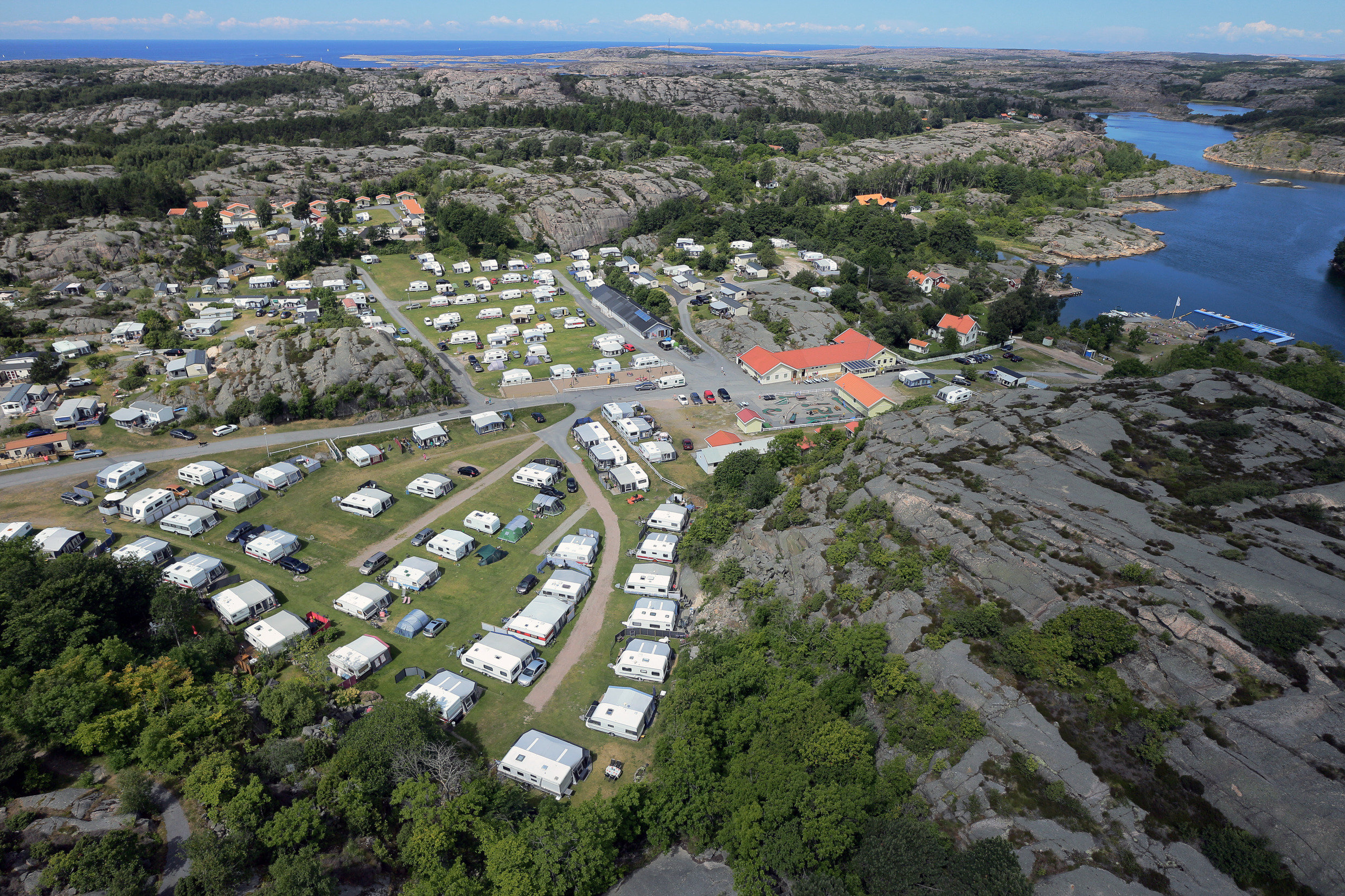 Luchtfoto van een camping aan zee. Caravans staan netjes in rijen geparkeerd.