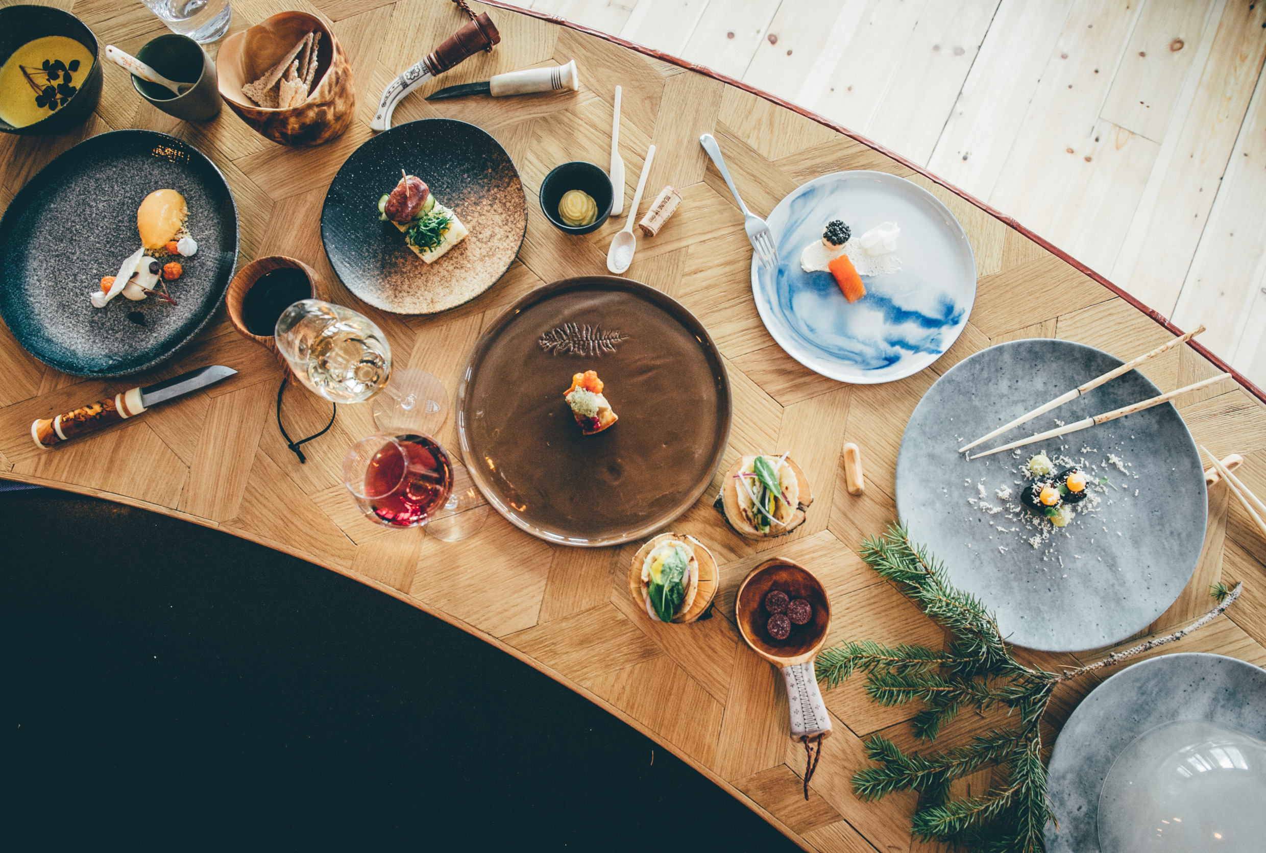 Ein Holztisch mit Essen, Tellern, Weingläsern und Besteck.