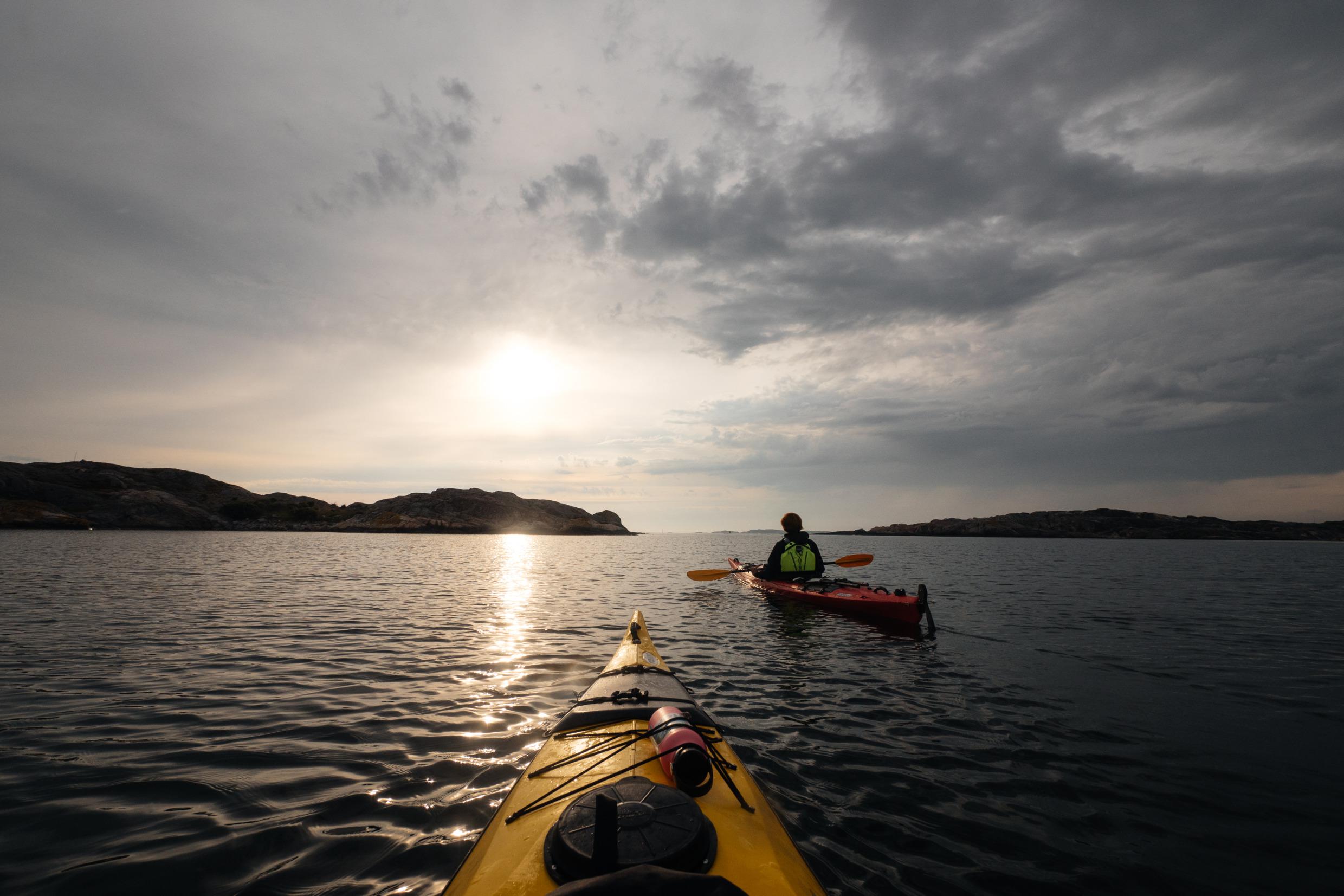 De voorkant van een kajak in het water. Iemand anders in een kajak verderop.